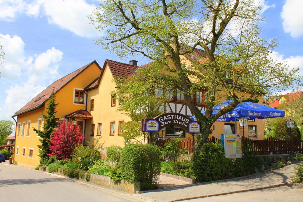 a yellow building with a blue umbrella in front of it at Gasthaus zur Linde in Rothenburg ob der Tauber