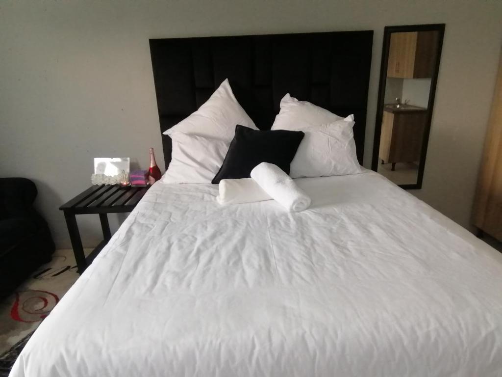 a white bed with black and white pillows at Serenity Airb&b Protea Glen in Soweto