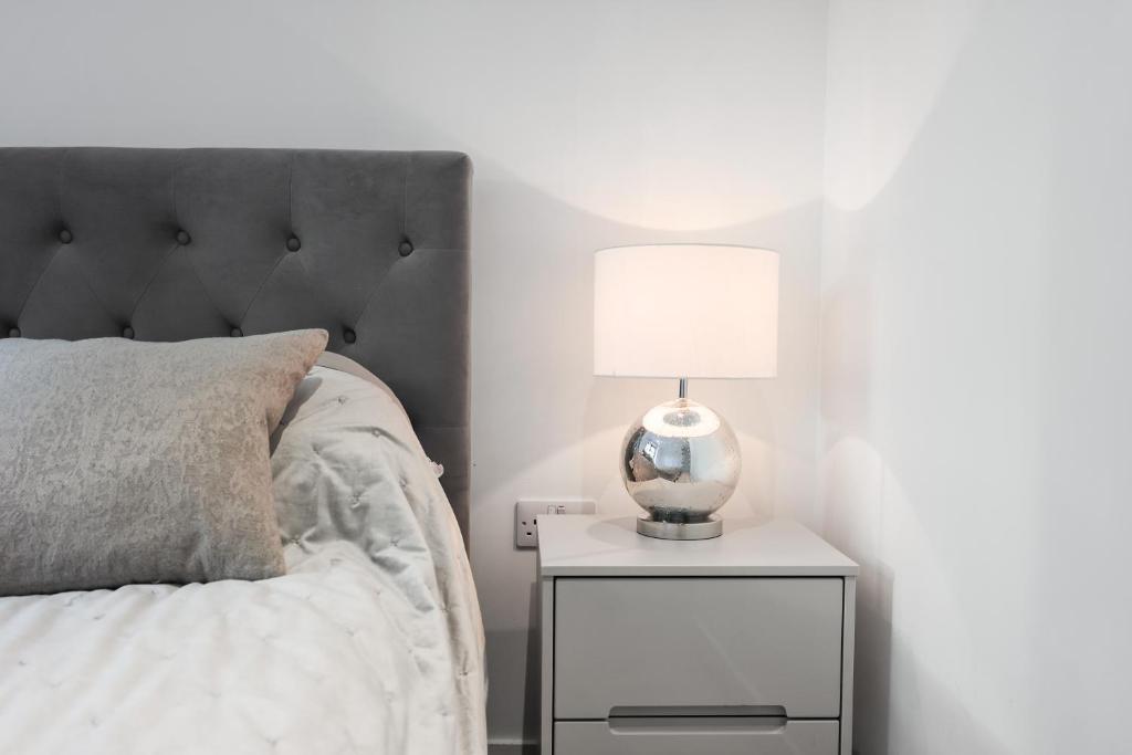 a bedroom with a bed and a lamp on a night stand at Riverside View Apartments in London