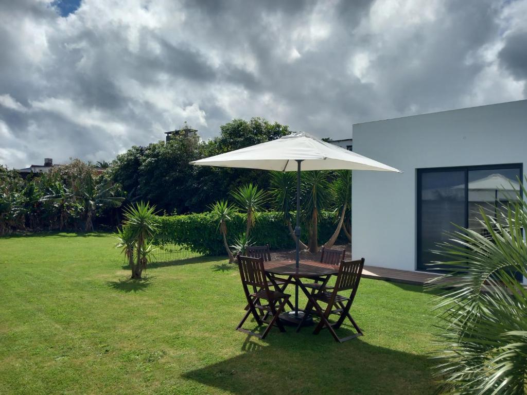 a table and chairs under an umbrella in a yard at Impeccable 1 Bed Villa in Ribeira Grande in Ribeira Grande