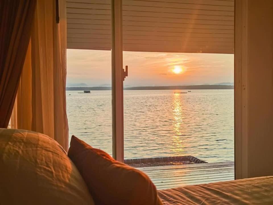 a bedroom with a window looking out at the ocean at Satun Sea Balcony ระเบียงเล 