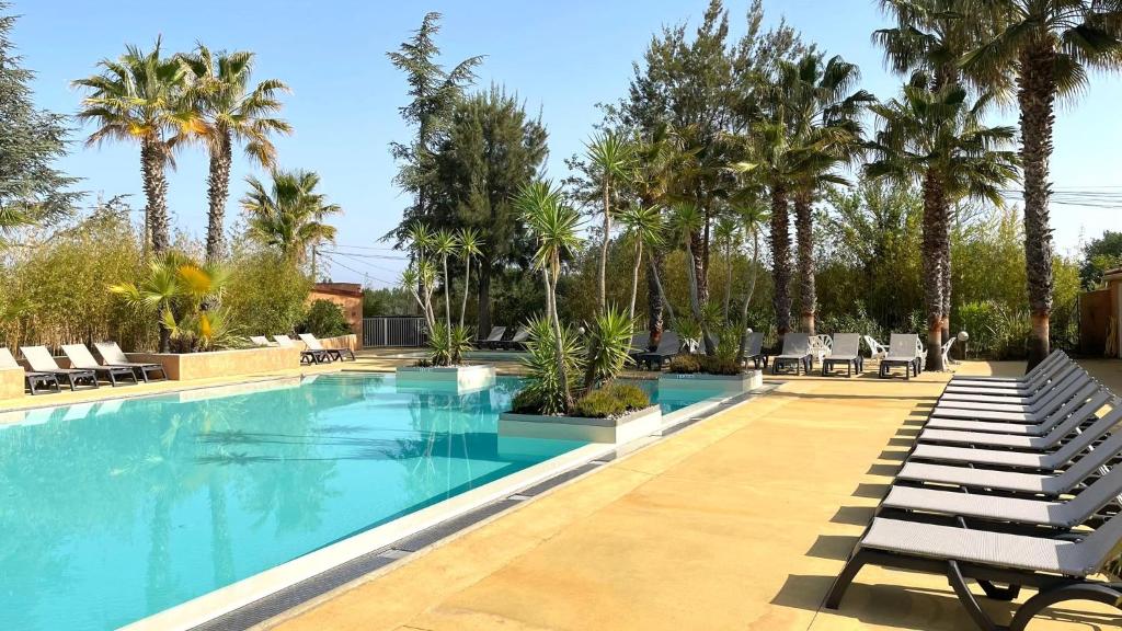 a swimming pool with lounge chairs and palm trees at Domaine La Pinède Enchantée in Argelès-sur-Mer
