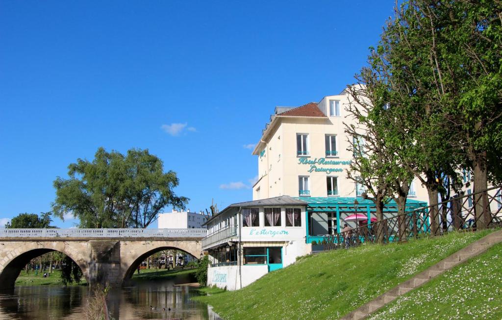 a building next to a river with a bridge at Hôtel L'Esturgeon in Poissy