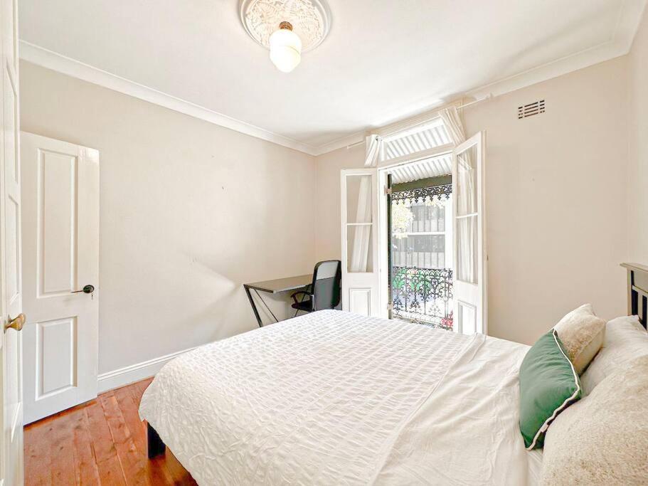 a white bedroom with a bed and a window at Pyrnmont Terrace & Townhouse in Sydney