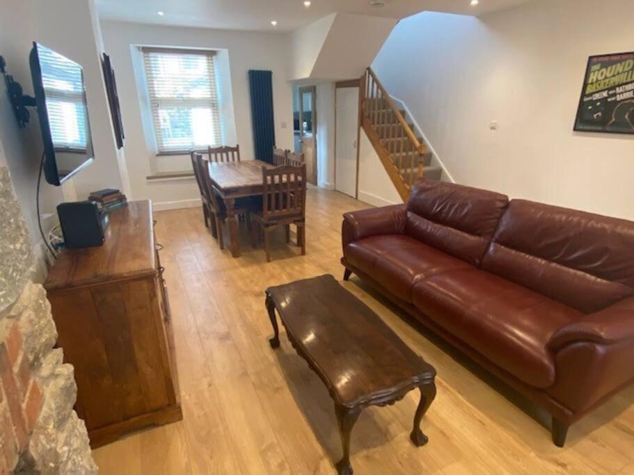 a living room with a brown leather couch and a table at Ivybridge Cottage in Ivybridge