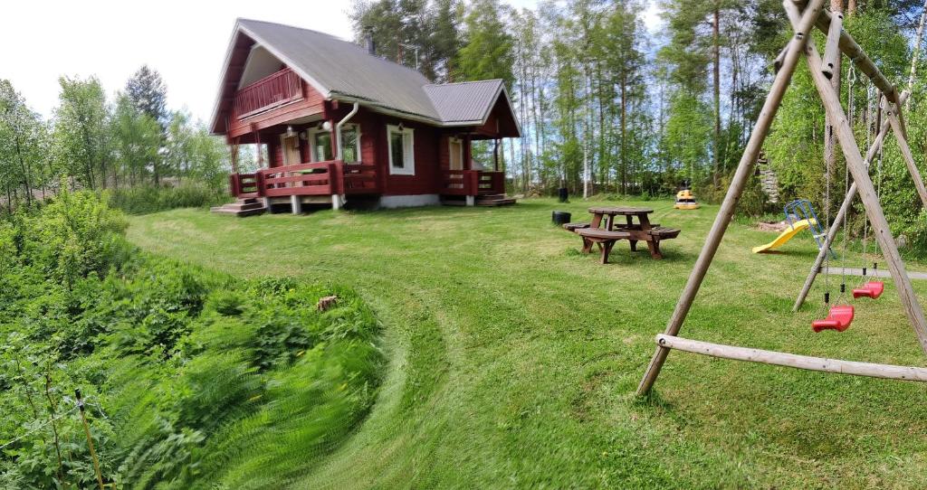 eine rote Hütte mit einem Picknicktisch und einem Spielplatz in der Unterkunft Kivitasku in Kalajoki