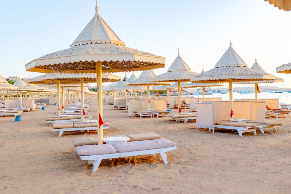 The Grand Hotel, Hurghada في الغردقة: شاطئ فيه كراسي ومظلات على الرمال