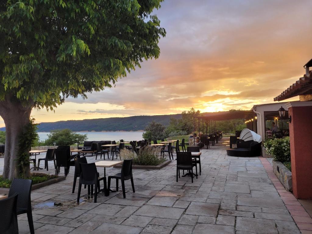 a patio with tables and chairs with a sunset in the background at Auberge des Salles in Les Salles-sur-Verdon