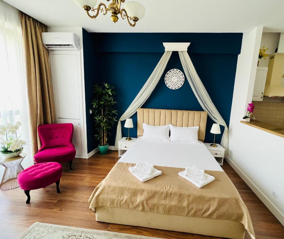 - une chambre avec un grand lit et une chaise rouge dans l'établissement Luxury Studio Mamaia Nord, à Mamaia Nord – Năvodari