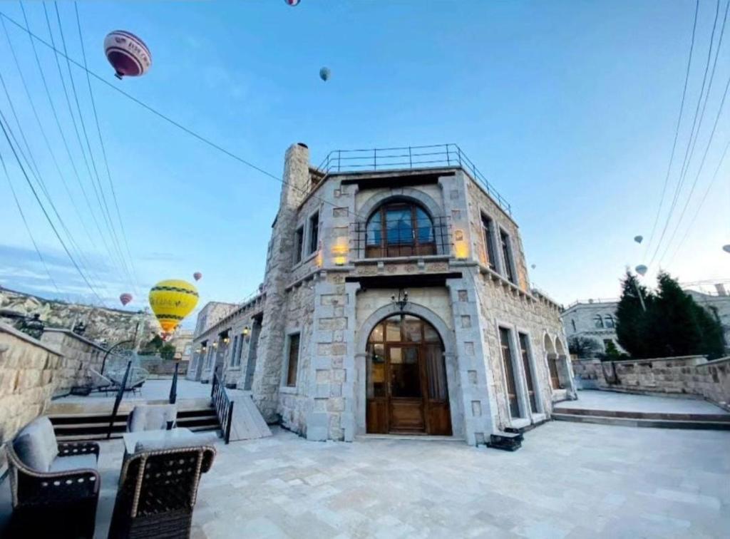 a large stone building with a door and a kite in the sky at Premium Cappadocia House in Goreme