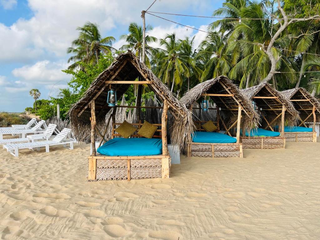 a row of huts on a beach with white chairs at Windy Waves Kite Beach & Nature Resort in Kalpitiya