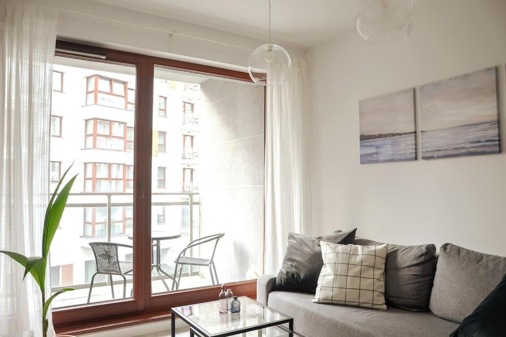 a living room with a couch and a table and a window at Platinum Jaglana Apartment - Wyspa Spichrzów in Gdańsk