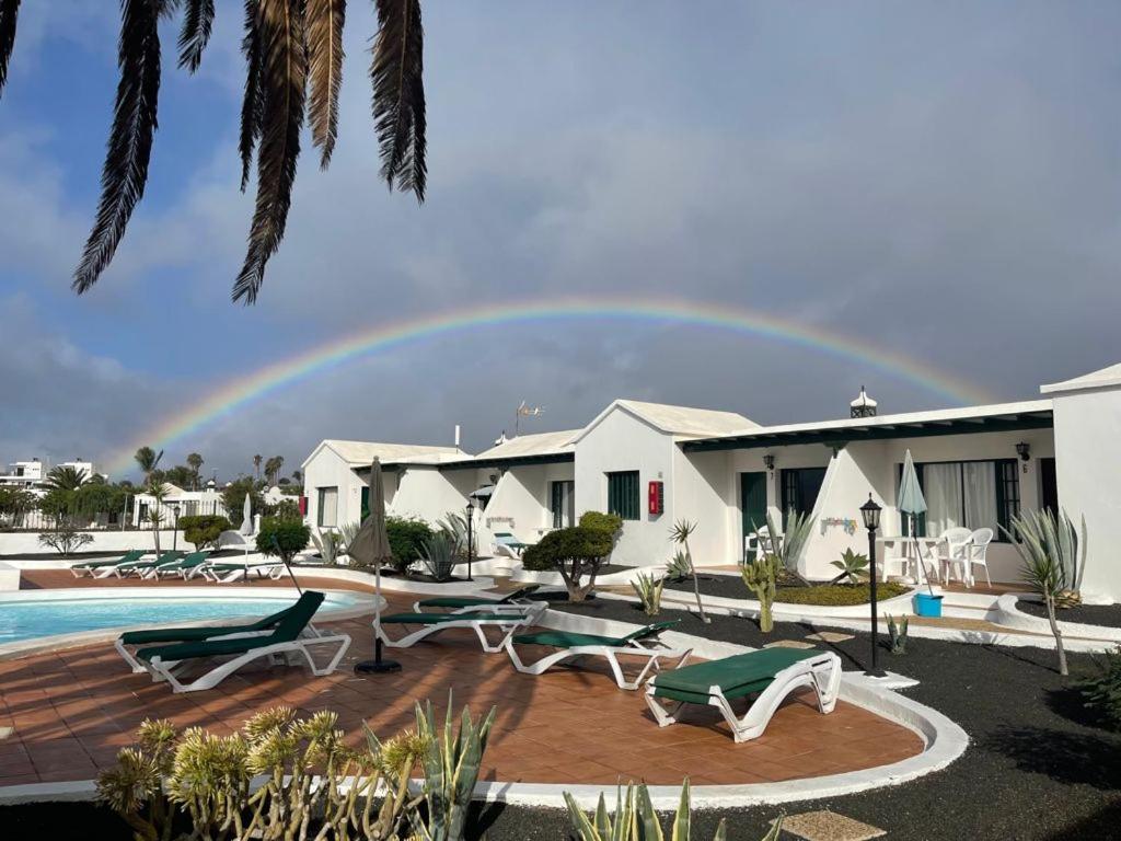 un arco iris en el cielo sobre una casa con piscina en Bungalows Doble UVE, en Tías