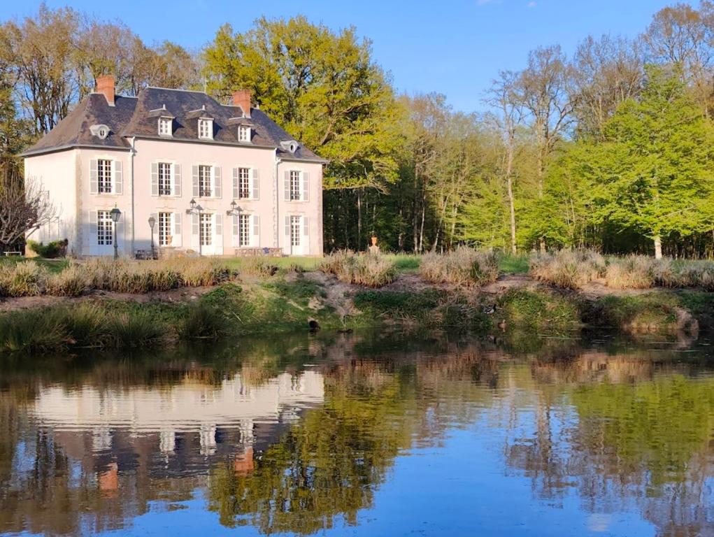 an old house is reflected in the water of a lake at Domaine de Charnay Plaisance Sologne in Vierzon