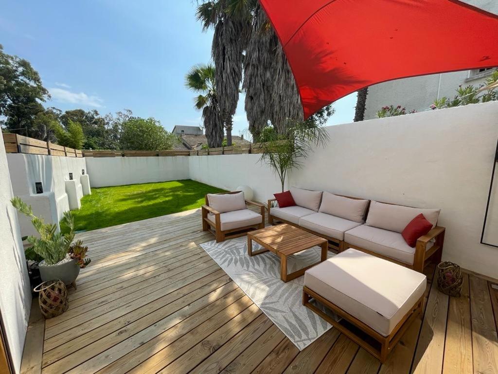 d'une terrasse avec un canapé et un parasol rouge. dans l'établissement Mini Villa Indépendante à 350m de la mer (LAX), à Lucciana