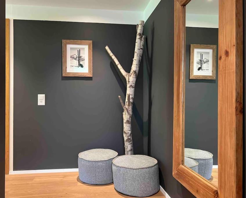 a room with a mirror and two stools and a tree at the NEST flims in Flims