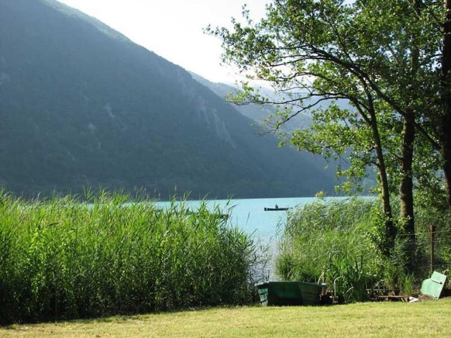 een uitzicht op een meer met een boot op het water bij Chalet les pieds dans l'eau Lac Aiguebelette in Nances