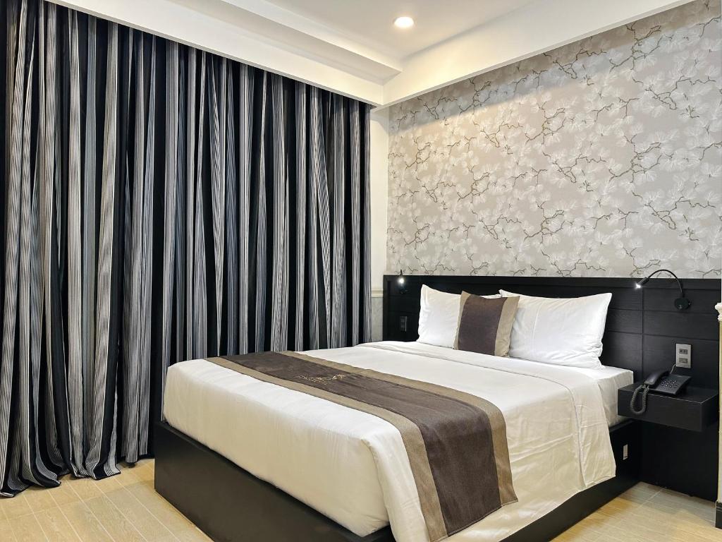 - une chambre avec un lit et un mur avec des rideaux dans l'établissement LION 8 Hotel, à Cần Thơ