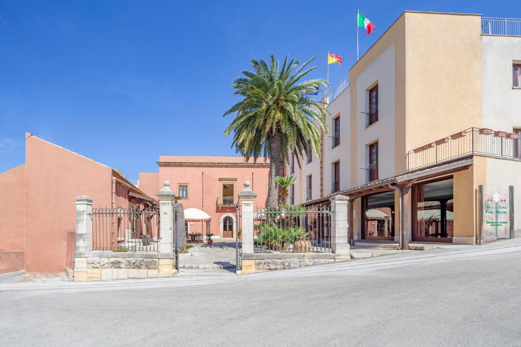 a street in a town with a palm tree and buildings at Villa Zina Family Resort in Custonaci