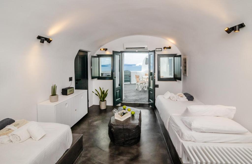 ein weißes Zimmer mit 2 Betten und einem Tisch in der Unterkunft Callista Villa in Oia