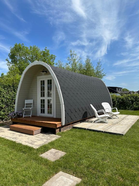 a dome shaped house with two chairs in the grass at LODGE, een super knus tiny house, nabij vaarwater en haven! in Belt-Schutsloot