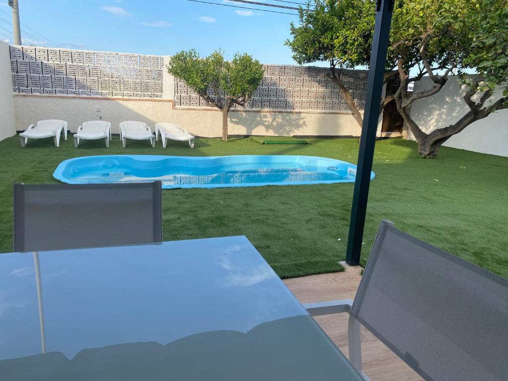 una piscina en un patio con sillas y mesa en vistalmar 1 casa verde en San Juan de Alicante