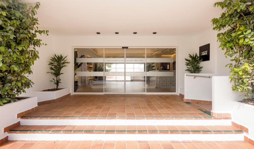 an empty lobby of a building with plants at Ilunion Menorca in Cala Galdana