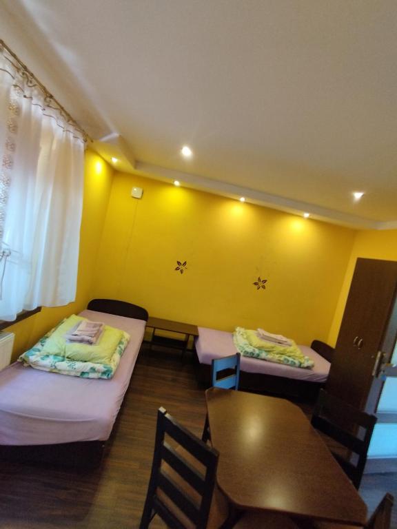 two beds in a room with a yellow wall at NOCLEGI ELA in Sieradz