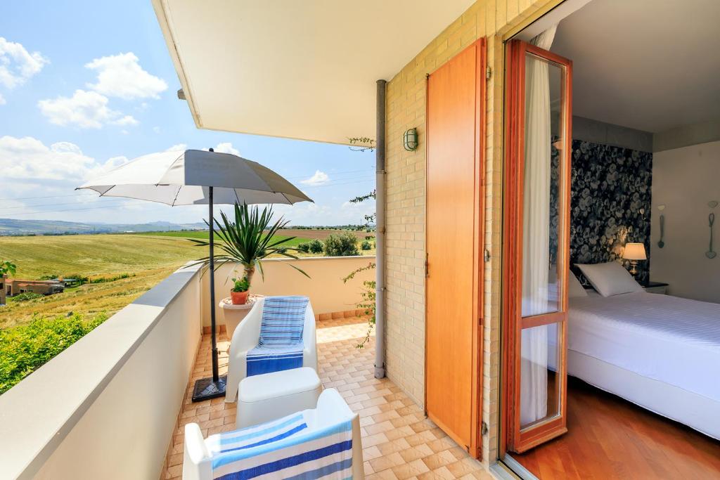 um quarto com uma varanda com uma cama e um guarda-chuva em B&B Il Tiglio em Porto SantʼElpidio