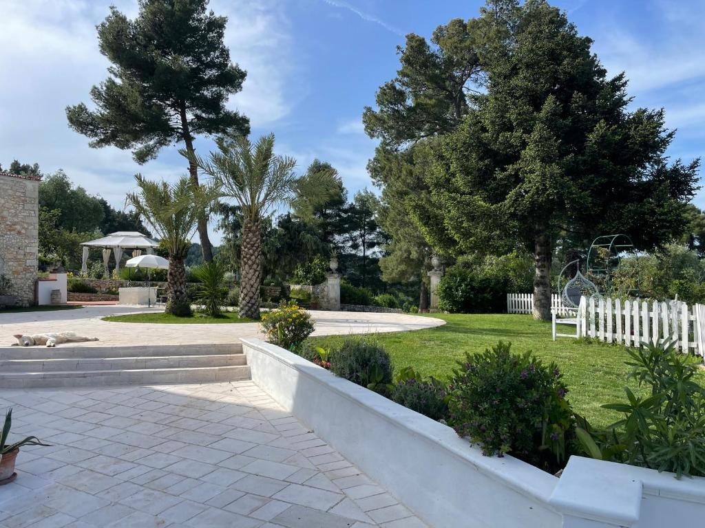 a garden with a white fence and trees at Novecento Country House in Vieste