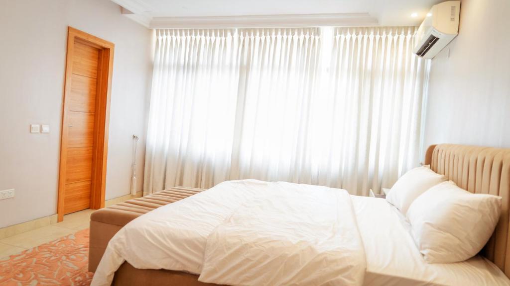 ein Schlafzimmer mit einem weißen Bett und einem Fenster in der Unterkunft Ruby and Pearl by Flair Apartments in Lagos