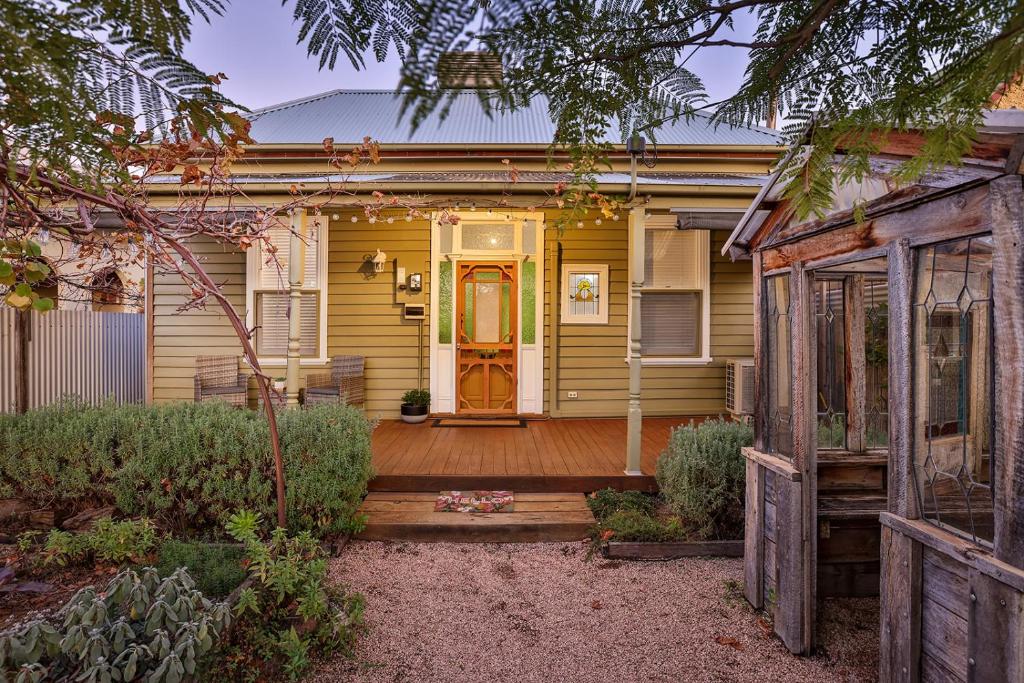 a yellow house with a wooden porch and a door at Mellorie's on Lemon in Mildura