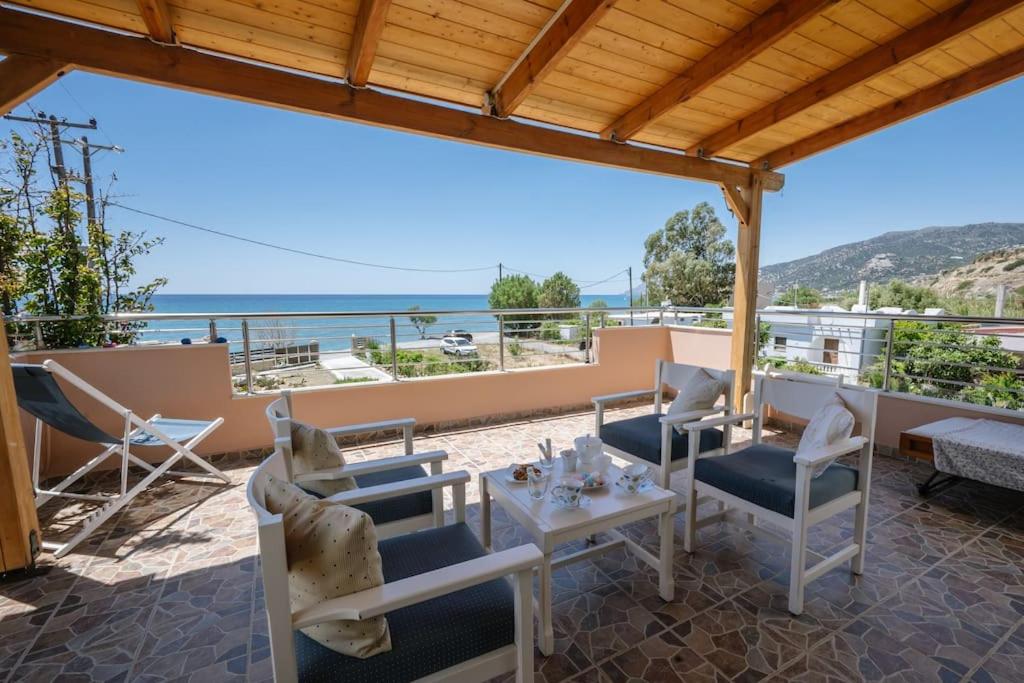 a patio with chairs and tables and a view of the ocean at Villa Kyma by the sea, in South Crete in Keratokampos