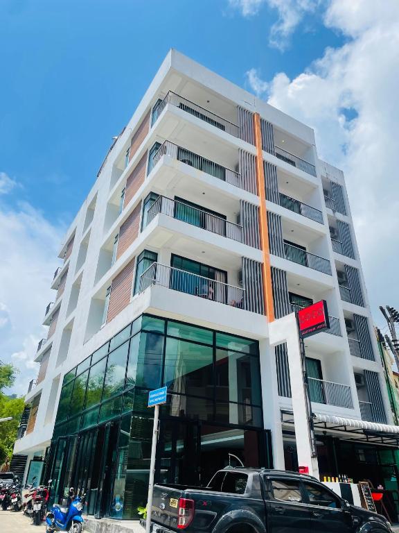 a tall white building with cars parked in front of it at Coco boutique hotel in Patong Beach
