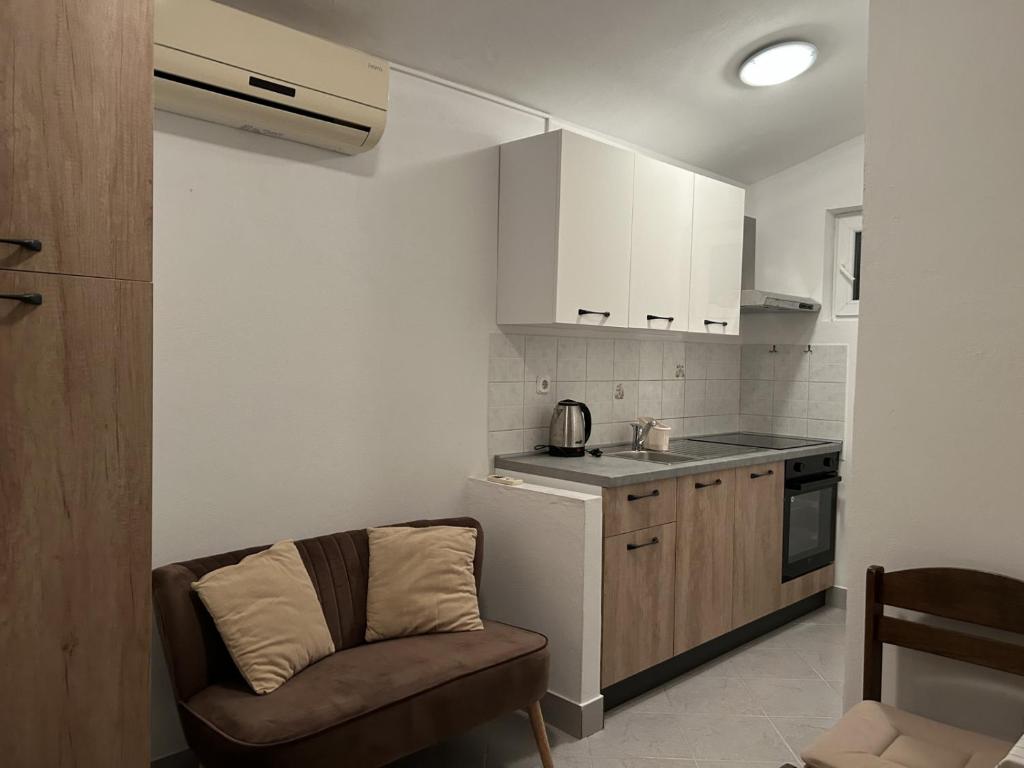 een kleine keuken met een stoel en een wastafel bij Apartment in Biograd na Moru with Terrace, Air conditioning, Wi-Fi (4801-2) in Biograd na Moru