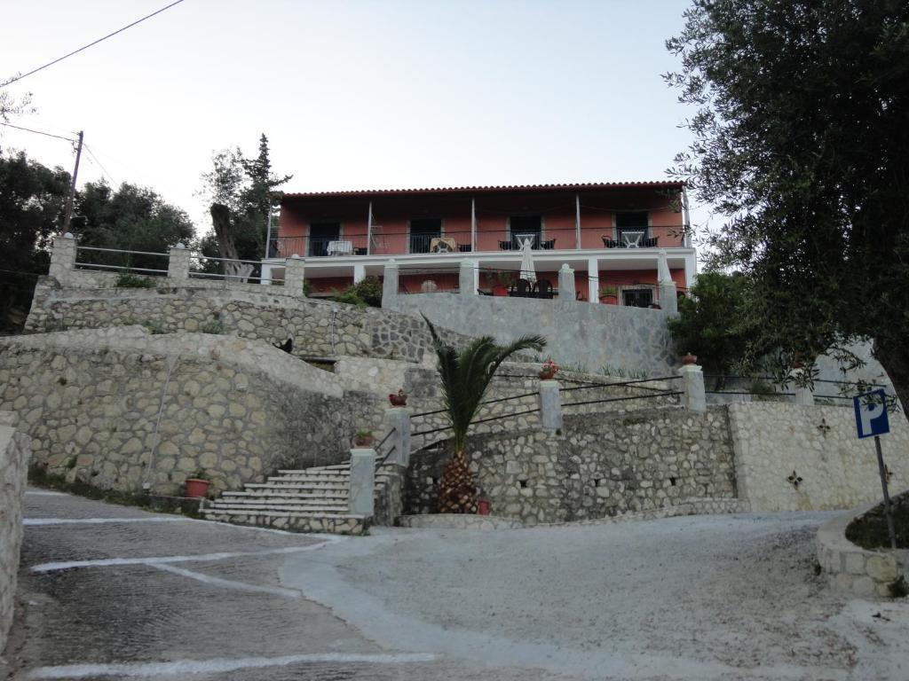 un mur en pierre avec un bâtiment en arrière-plan dans l'établissement Stamatela Studios, à Paleokastritsa