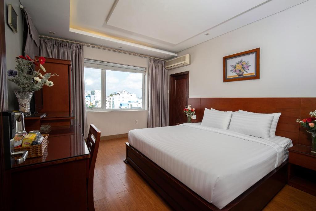 Un dormitorio con una gran cama blanca y una ventana en Van Ha Hotel en Ho Chi Minh