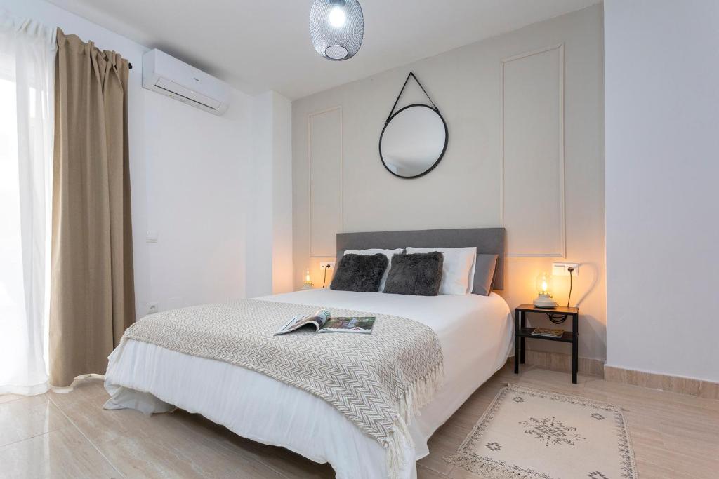 a white bedroom with a bed and a mirror at LaTerraza de Ollerias in Málaga