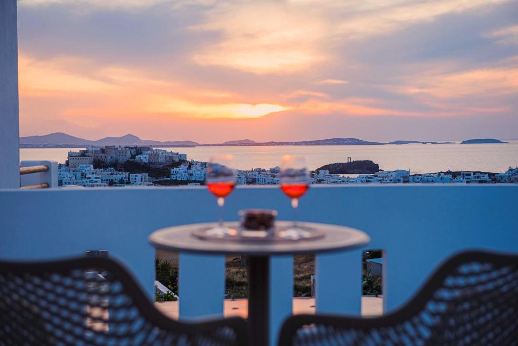 a table with two glasses of wine on a balcony at Petros Studios & Suites in Naxos Chora