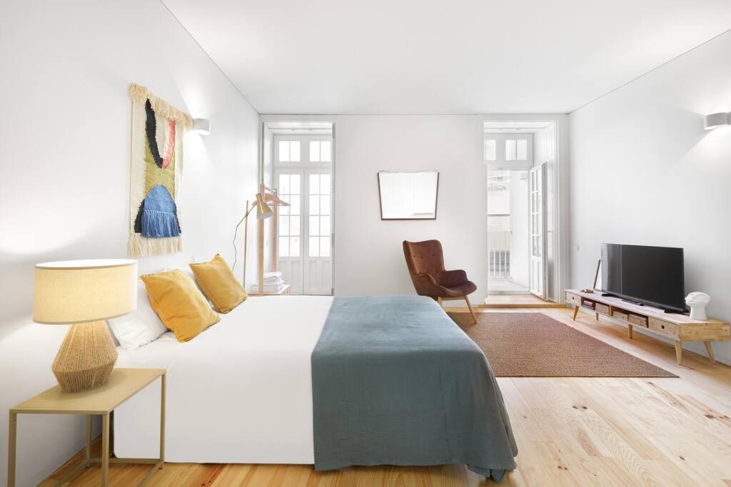 een witte slaapkamer met een groot bed en een televisie bij InBloom Apartments 3 in Porto