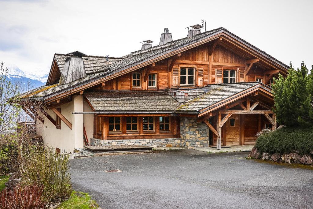 een groot houten huis met een oprit ervoor bij Le Chalet Hôtel Cordon Adults Only in Cordon