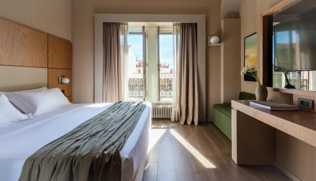 ミラノにあるワールドホテル クリストフォロ コロンボの大きなベッドと窓が備わるホテルルームです。