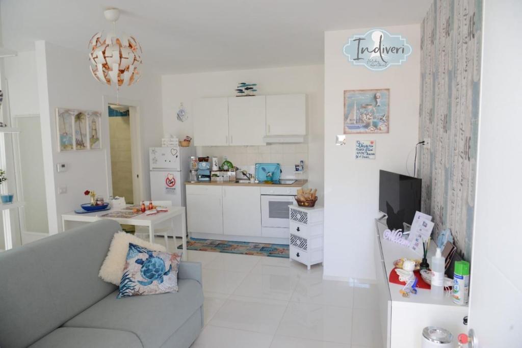 a white living room with a couch and a kitchen at Indiveri holiday apartaments Melissa by STHEY in Polignano a Mare