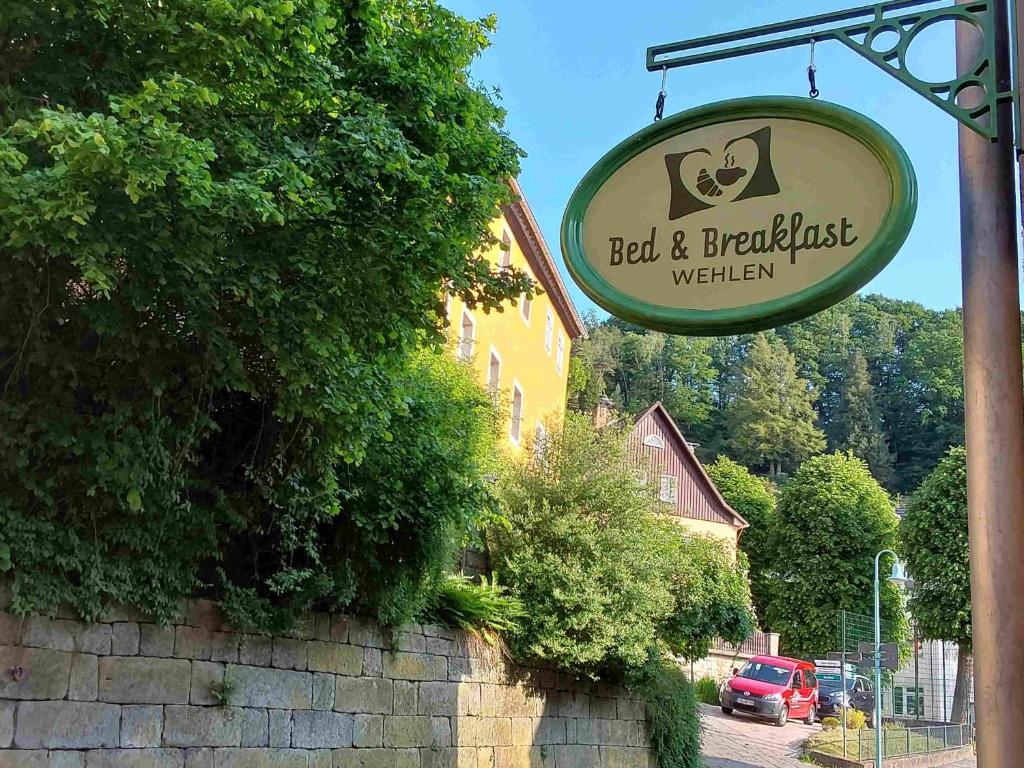 um sinal para um alojamento de acomodação e pequeno-almoço com um edifício em Bed and Breakfast Wehlen em Stadt Wehlen