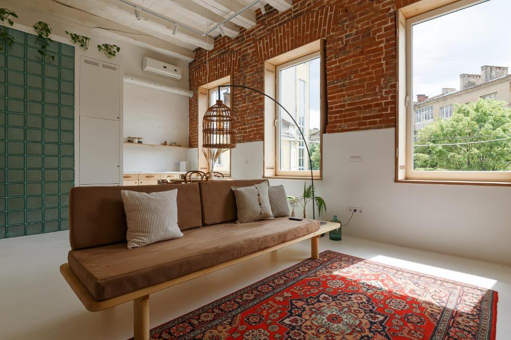 a living room with a brown couch and a brick wall at Loft Apartment in Ivano-Frankivsʼk