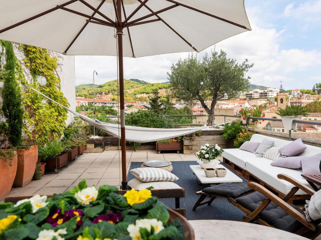 a patio with a couch and an umbrella and flowers at Loft Bouquet Alella mar y montaña 25 min a BCN in Alella