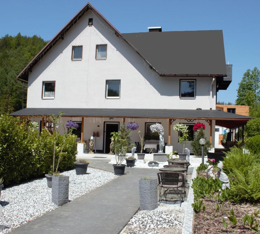 uma grande casa branca com um pátio com plantas em Waldpension Pfeiferhaus em Warmensteinach