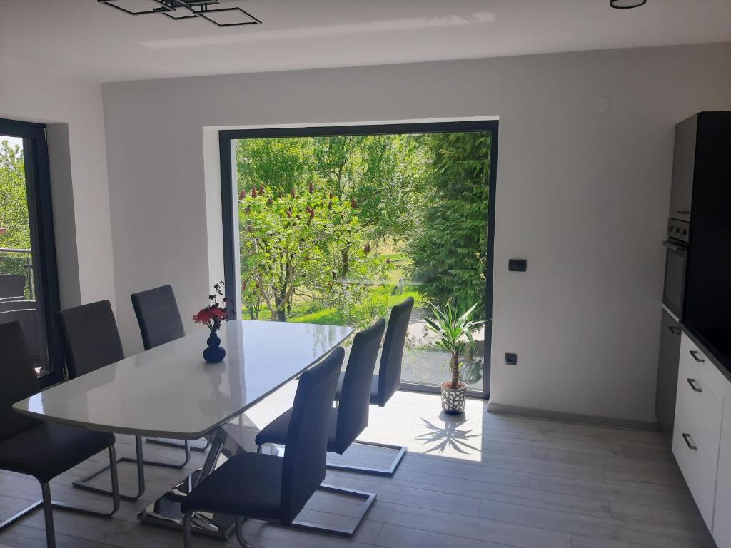 a dining room with a table and chairs and a large window at House Under The Maple Tree in Vitanje