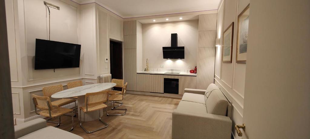 ein Wohnzimmer mit einem Tisch, Stühlen und einem TV in der Unterkunft Marcora 6 g luxury living in Mailand