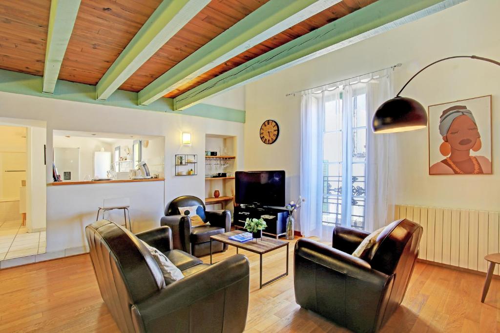 a living room with leather chairs and a tv at Uncourtsejour - Nîmes la Rome française in Nîmes